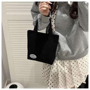 Detail of black corduroy tote bag showing the white FANYISSA letter patch decoration