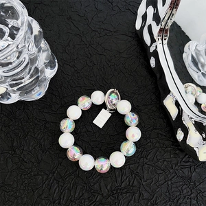Detail of beaded phone strap with creamy white beads, aurora spheres, and metal tag charm