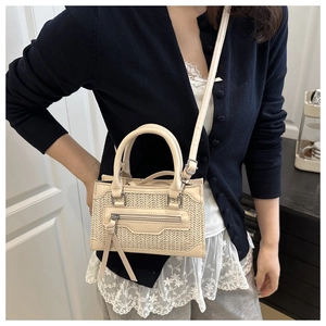 Detailed view of woven crossbody bag with leather trim and tassel on a female model
