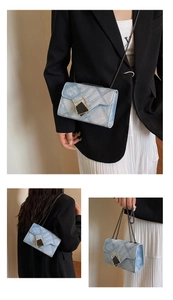 Detail view of blue denim texture crossbody bag with gold-tone hardware and chain strap