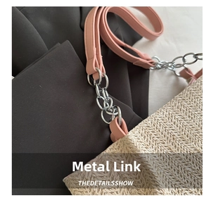 Detail of woven straw tote showing pink faux leather strap with silver metal chain link