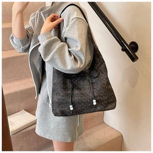 Detail of denim hobo bag with polka dot texture and decorative bow and bead charms