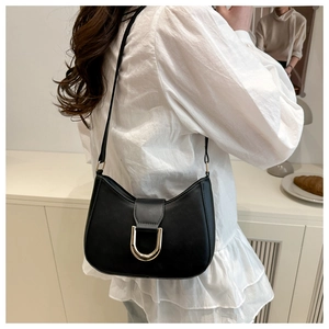 Detail of minimalist black crescent underarm bag with gold U-shaped metal buckle on model