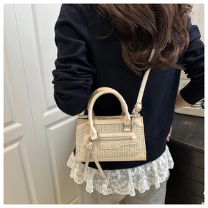 Detail of beige woven straw handbag with leather trim and long tassel decoration