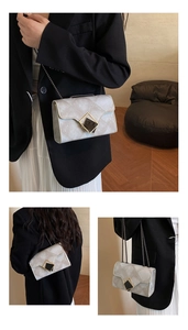 Detail of grey diamond-quilted crossbody bag with geometric metal lock and chain strap