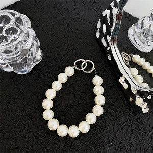 Detailed shot of large round pearls on a stylish mobile wrist strap with silver metal rings
