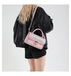 Pink sequined crossbody bag detail with golden metal ring lock and leather texture