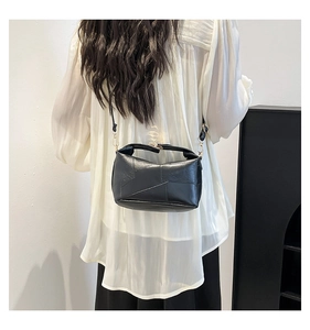 Detailed view of black patchwork leather shoulder bag with geometric stitching and top handle
