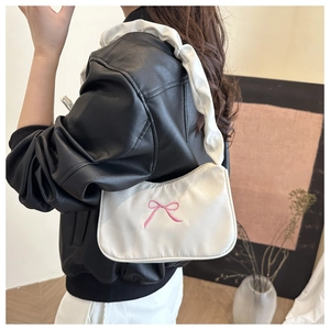Détail du sac sous le bras en similicuir blanc avec broderie nœud rose et bandoulière à volants