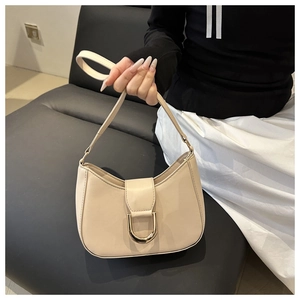 Detail of a creamy white crescent hobo bag featuring a gold U-shaped metal buckle closure