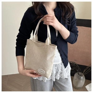 Detail of FANYISSA embroidery on cream corduroy tote bag with woven handles