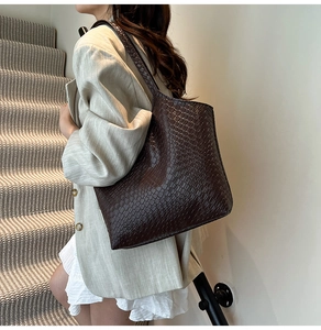 Detail view of large brown crocodile embossed tote bag worn with a stylish beige outfit