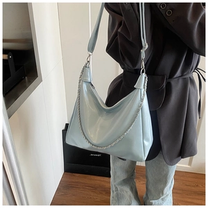Side view of light blue glossy leather hobo bag with silver chain on model in suit
