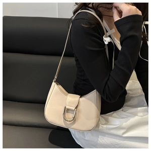 Detail view of a beige hobo underarm bag with gold U-shaped buckle on a smooth leather finish