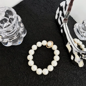 Detailed view of glossy white pearls with gold clasp on textured black background