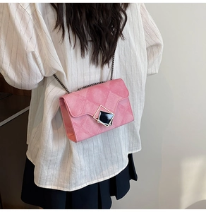 Close-up of pink quilted crossbody bag featuring silver geometric clasp and chain strap