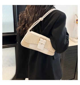 Detail of white crocodile embossed shoulder bag with square metal buckle on black blazer