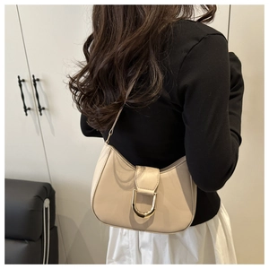 Close-up of cream leather hobo bag featuring a distinctive gold U-shaped metal buckle