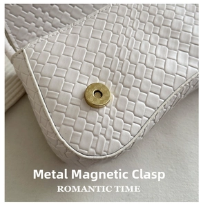 Close-up of white woven leather texture and golden magnetic buckle on baguette bag