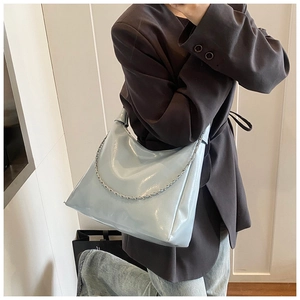 Side view of light blue glossy patent leather shoulder bag with fine chain decoration