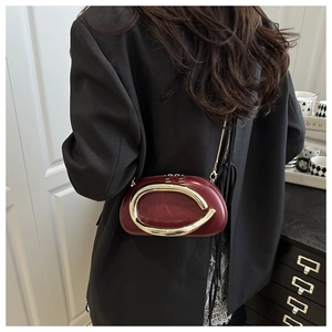 Detailed view of a burgundy chain box bag worn as a shoulder bag on a model