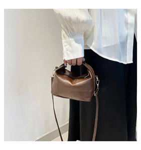 Detail of brown leather handbag with geometric stitching and golden hardware accents