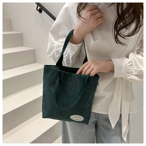 Detail of dark green corduroy tote bag featuring striped texture and fabric label