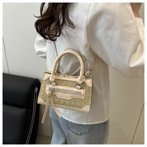 Detail of a beige woven crossbody bag with leather trim worn by a model in casual attire