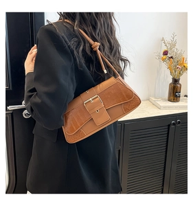 Detail of caramel crocodile embossed baguette bag with gold buckle and knotted shoulder strap