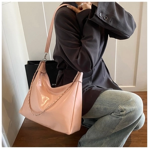 Detail of pink patent leather hobo bag featuring glossy finish and metal chain accents