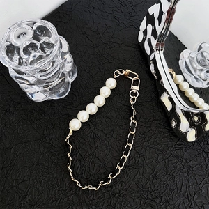 Detail of luxury phone strap with white pearls and gold metal leather chain weave