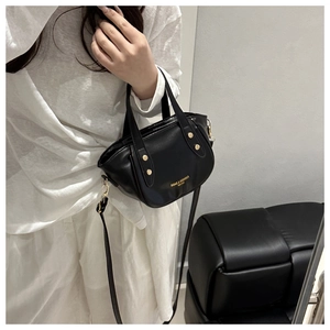 Gros plan détaillé du sac seau rétro en cuir noir avec rivets dorés et lettrage de marque
