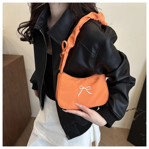 Dettaglio borsa arancione in tessuto con fiocco bianco e tracolla arricciata alla moda