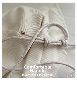 Macro shot of white woven leather handle with gold metal tips on elegant shoulder bag