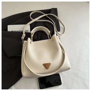 Détail du sac fourre-tout blanc crème en cuir PU texturé avec plaque logo en bronze