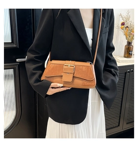 Detail of vintage brown crocodile embossed baguette bag with golden buckle on model