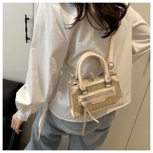 Detail of crossbody straw woven bucket bag with long fringe zipper and leather handles