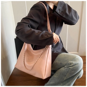 Detail of pink patent leather tote bag featuring a decorative silver chain strap