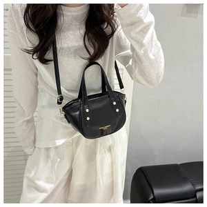 Detail of black leather half-moon bucket bag with gold studs and shoulder strap