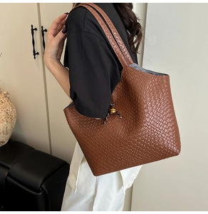 Détail d'un grand sac cabas tressé marron avec motif damier porté à l'épaule