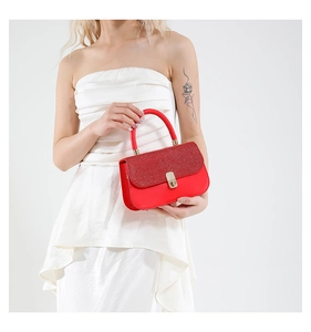 Detail of red sequined handbag with gold metallic clasp and smooth leather handle