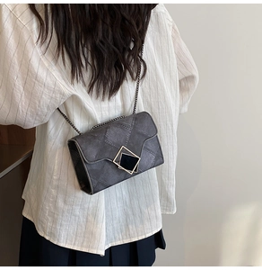 Detail of grey crossbody bag with diamond quilted texture and golden geometric clasp