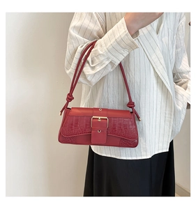 Detail of red shoulder bag featuring crocodile texture and gold square buckle detail