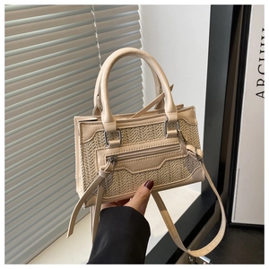 Detail of a beige faux leather and straw woven crossbody bag with knotted zipper pull