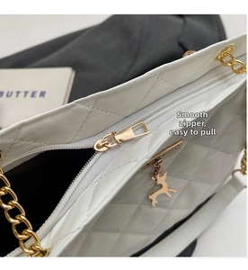 Detailed shot of a white quilted bag with a golden zipper and a cute deer charm