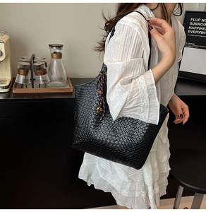 Detail of black woven tote bag with a decorative silk scarf on a stylish shoulder strap
