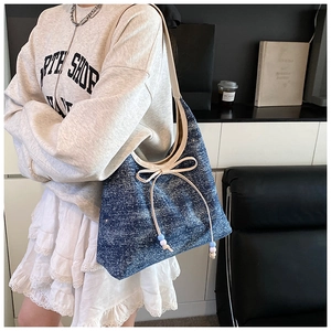Detail of blue denim hobo bag with glitter finish and decorative beige bow tie strap