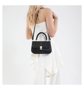 Detailed back view of a woman wearing a black glitter crossbody bag with gold metal buckle