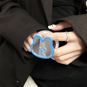 Détail d'un support de téléphone miroir lapin bleu tenu à la main sur fond sombre