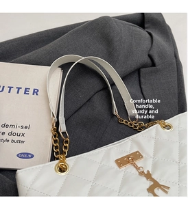 Detail of white quilted handbag with golden deer charm on a stylish blazer background